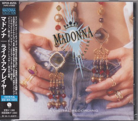 Japanische Schriftzeichen links, "MADONNA LIKE A PRAYER" mittig. Schmuck und Jeans im Hintergrund.
