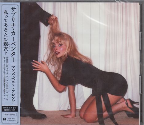 Eine Frau kniet am Boden, ein Mann hält ihr Haar hoch. Links steht japanischer Text über Musik.