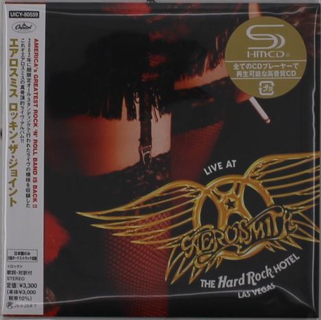 Text: "AMERICA'S GREATEST ROCK'N ROLL BAND IS BACK!!" "LIVE AT THE HARD ROCK HOTEL LAS VEGAS"  
Bild: Leder, Netzstrümpfe, goldene Flügel.