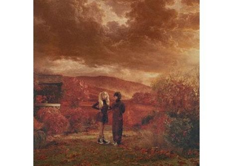 Zwei Personen stehen in einer herbstlichen Landschaft unter einem dramatisch bewölkten Himmel, umgeben von roten Blättern.