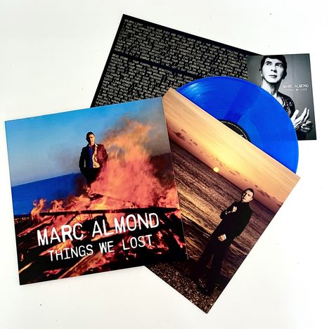 "Marc Almond, Things We Lost." Ein Albumcover zeigt eine Person vor einem Feuer, eine blaue Schallplatte liegt dabei.