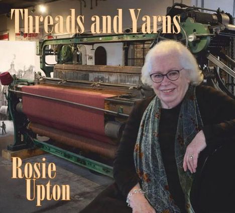 „Threads and Yarns“, „Rosie Upton“. Eine lächelnde Frau vor einem großen, altmodischen Webstuhl.