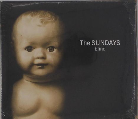 Text: The SUNDAYS blind. 
Ein sepiafarbenes Bild eines antiken Puppenkopfes mit fixierendem Blick.