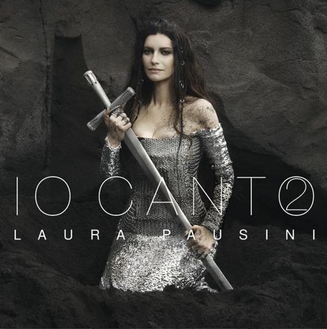 Text: "IO CANTO", "LAURA PAUSINI". Eine Frau in silbernem Kleid hält ein Schwert, umgeben von dunkler Erde.
