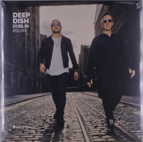 "Deep Dish Dublin #GU49". Zwei Männer in dunkler Kleidung und Sonnenbrillen gehen auf einem Kopfsteinpflaster.