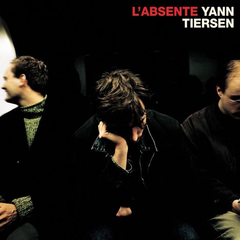 "L'Absente Yann Tiersen" steht oben. Drei Personen sitzen nebeneinander, die mittlere mit gesenktem Kopf.