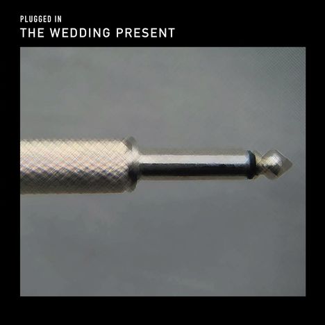 Text: "Plugged In. The Wedding Present." Darstellung eines metallischen Klinkensteckers horizontal ausgerichtet.