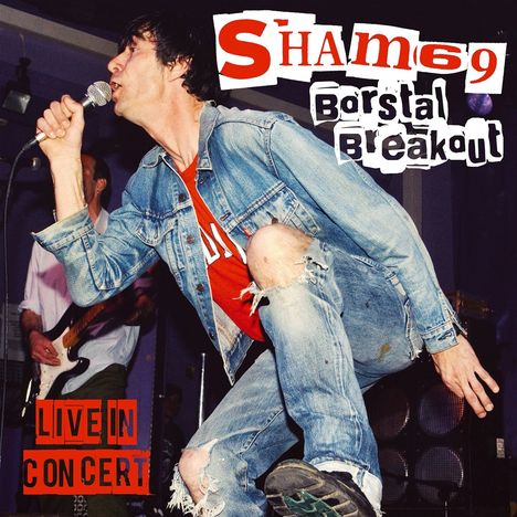 "Sham 69", "Borstal Breakout", "LIVE IN CONCERT". Ein Mann in Jeansjacke kniet, singt in ein Mikrofon.