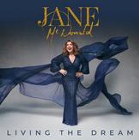 Text: "JANE McDonald" und "LIVING THE DREAM." Frau in blauem Kleid mit fließendem Stoff, posierend.