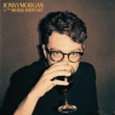 Text: "JONNY MORGAN & THE MORAL SUPPORT." Ein Mann mit Brille hält ein Weinglas, das er gerade trinkt.