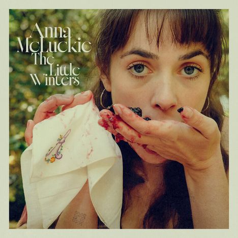 Text: "Anna McLuckie The Little Winters". Frau isst Beeren, Hände sind rot gefleckt, hält ein besticktes Taschentuch.