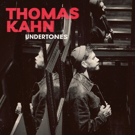 Text: "THOMAS KAHN UNDERTONES". Ein Mann im Profil, mehrfach in Spiegeln reflektiert, trägt eine Jacke und Mütze.