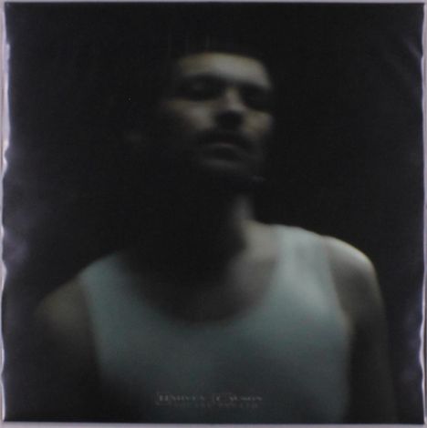 Unscharfes Porträt einer Person in weißem Tanktop vor dunklem Hintergrund.