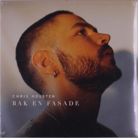 Text: "CHRIS HOLSTEN BAK EN FASADE". Seitenprofil eines Mannes mit Bart, Kopf nach oben geneigt, im sanften Licht.