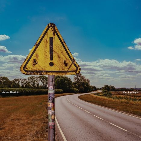 "James Marriott" und "Warning Signs" stehen in weiß. Ein gelbes Dreieck mit Ausrufezeichen an einer Landstraße.