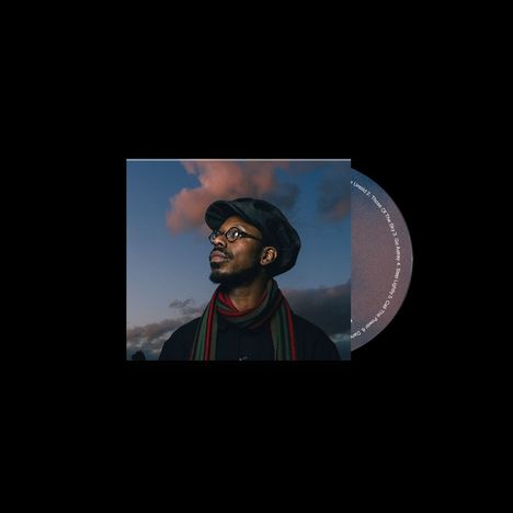 Ein Mann mit Brille und Mütze blickt nach oben, vor einem dämmernden Himmel. Rechts ist eine Teilscheibe sichtbar.