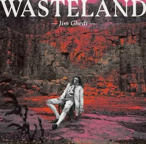 "WASTELAND" und "Jim Ghedi" stehen im Vordergrund. Eine Person sitzt vor einer steinigen, rötlich gefärbten Felskulisse.