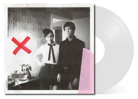 Ein großes rotes X ist auf einem Schwarzweißfoto von zwei Personen angebracht. Eine Lampe und Tapete im Hintergrund.