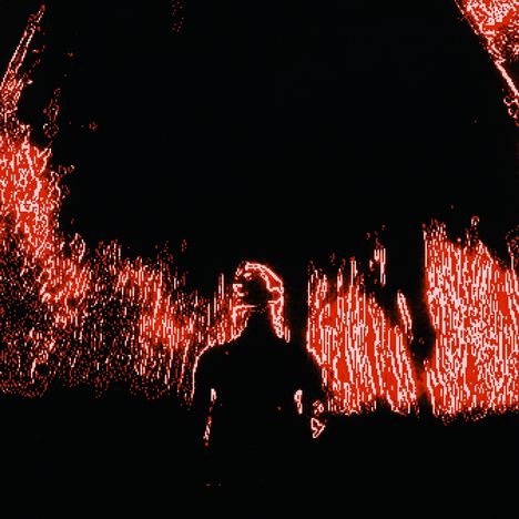 Eine Person steht in rotem Licht vor einem dunklen Hintergrund.