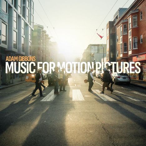 "ADAM GIBBONS MUSIC FOR MOTION PICTURES" steht auf einem belebten Straßenmotiv bei Sonnenuntergang mit Menschen.