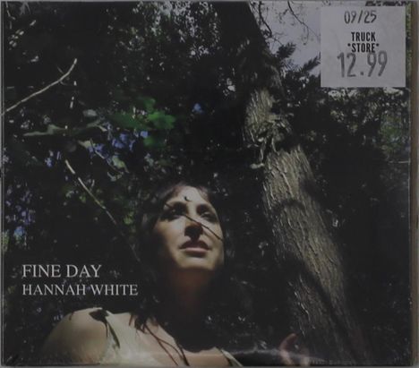"FINE DAY HANNAH WHITE" und "TRUCK STORE 12.99". Eine Frau im Wald schaut nach oben; Schatten und Sonnenlicht spielen.