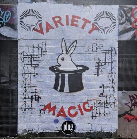 Text: "VARIETY MAGIC". Illustration eines Kaninchens in einem Zylinder, umgeben von grafischen Elementen.