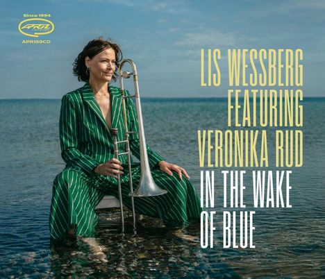 Lis Wessberg featuring Veronika Rud: In the Wake of Blue. Eine Frau im grünen Anzug sitzt mit Posaune im Wasser.