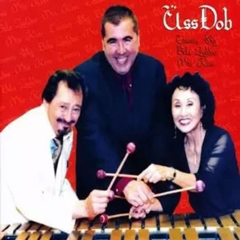 Text: "ÜssDob" und "Trown the Red Vodka on the Blue". Drei lächelnde Personen spielen gemeinsam Vibraphon.