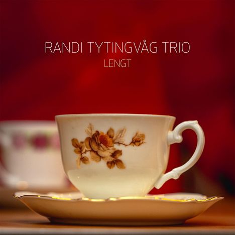 RANDI TYTINGVÅG TRIO, Lengt. Eine Teetasse mit Blumenmotiv auf Untertasse vor rotem Hintergrund.