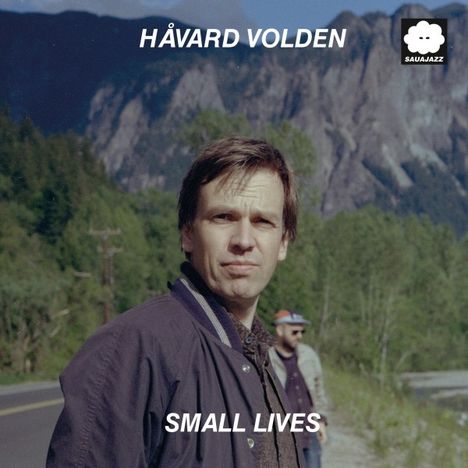 HÅVARD VOLDEN, SMALL LIVES. Im Vordergrund ein Mann, im Hintergrund Berge, Bäume und ein weiteres unscharfes Gesicht.
