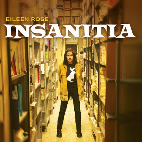 Text: "Eileen Rose INSANITIA". Eine Frau steht in einem Bücherregalgang, trägt eine Jacke und ein T-Shirt mit Tieraufdruck.