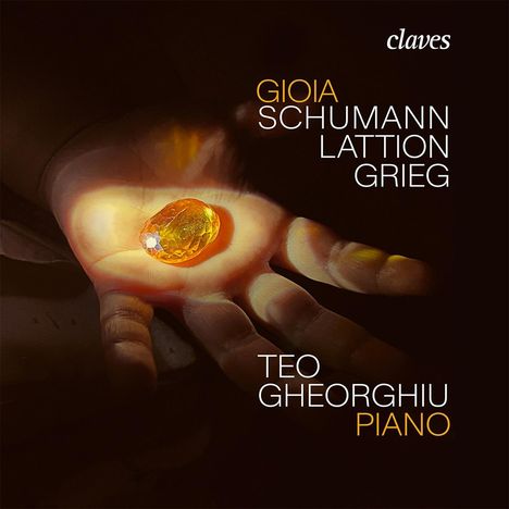 Texte: "GIOIA SCHUMANN LATTION GRIEG", "TEO GHEORGHUI PIANO". Im Hintergrund eine Hand hält einen leuchtenden, gelben Edelstein.