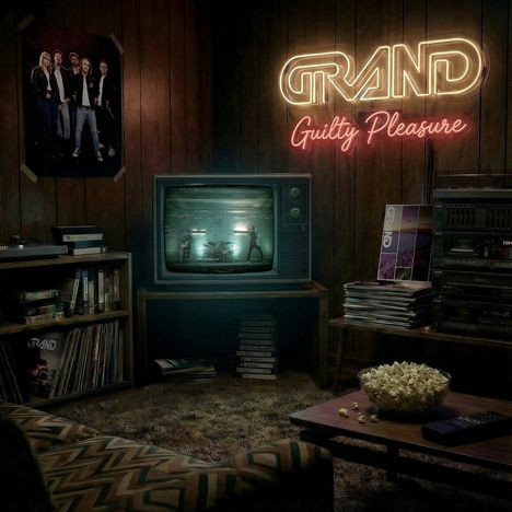 Text: "GRAND Guilty Pleasure." Eine gemütliche Retro-Wohnzimmerumgebung mit TV, Posters, Plattenspieler und Popcorn.