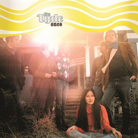 Text: "the Tyde once". Fünf Personen stehen vor einem Haus, eine Person sitzt im Vordergrund, Sonnenstrahlen scheinen durch.