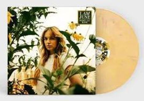 "I Am June" steht oben. Eine Frau mit langen Haaren ist von Pflanzen umgeben. Eine gelbe Vinyl-Schallplatte ist sichtbar.