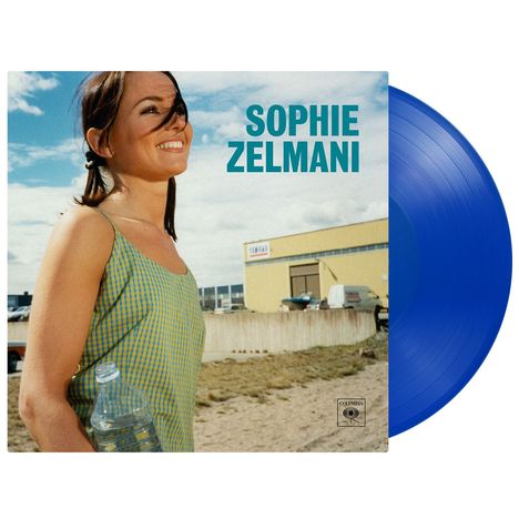 „Sophie Zelmani“ in türkisfarbener Schrift. Eine lächelnde Frau im Sommerkleid hält eine Wasserflasche; daneben eine blaue Schallplatte.