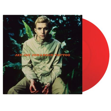"JAY-JAY JOHANSON TATTOO" in orange Schrift. Ein Mann in beiger Jacke sitzt inmitten von Pflanzen. Eine rote Schallplatte.