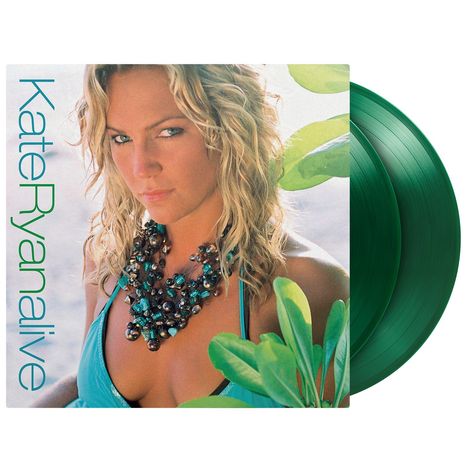 „Kate Ryan alive“ steht neben einer Frau in blauem Top mit einer auffälligen Halskette, umgeben von grünen Blättern.