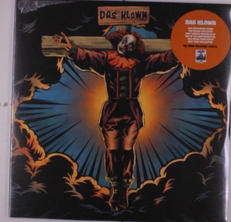 "DAS KLOWN" steht über einem clownartigen Charakter, der an ein Holzkreuz gebunden ist. Strahlendes Licht und Wolken.