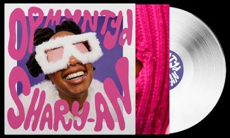 Aufschrift "OPMAATWERK SHARY-AN". Eine fröhliche Person mit großen, flauschigen Sonnenbrillen und einem weißen Vinyl.