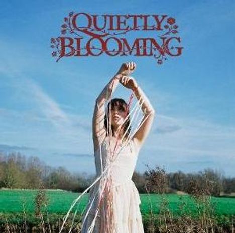 Text "Quietly Blooming"; Frau in weißem Kleid, hält Bänder hoch, steht auf Wiese mit blauem Himmel.