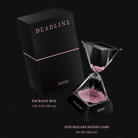 Text: "DEADLINE", "PACKAGE BOX 134×210×105 mm", "HOURGLASS MOOD LAMP 86×86×160 mm". Eine Sanduhr mit rosa Sand neben einer schwarzen Box.
