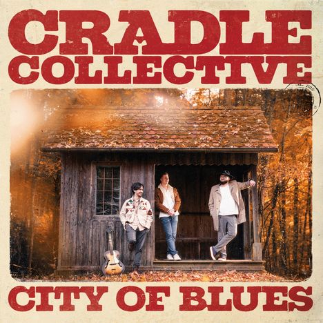 "CRADLE COLLECTIVE" und "CITY OF BLUES" in großen Buchstaben. Drei Männer vor einer Holzhütte im herbstlichen Wald.