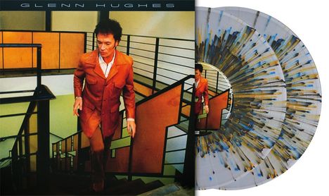 "GLENN HUGHES", "REISSUED SOUNDS". Ein Mann im braunen Anzug geht eine Treppe in einem modernen Gebäude hinauf.