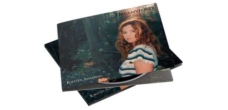 Text: "DREAMVIEWER, KRISTEN ADAMSON." Cover: Frau mit lockigem Haar im Wald, trägt gestreiftes Oberteil.