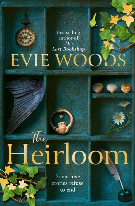 Ein Regal mit einer alten Uhr, Muscheln, einem Federkiel, Efeu und einem Flügel. "Evie Woods - The Heirloom" steht groß geschrieben.