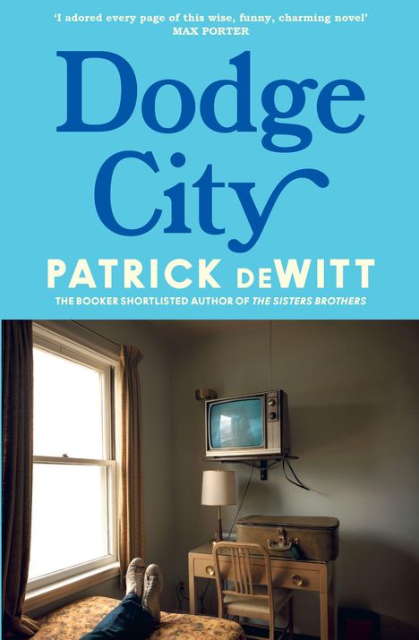 "Dodge City" und "Patrick deWitt" auf blauem Hintergrund. Zimmer mit Fernseher, Schreibtisch und Füßen auf Bett sichtbar.