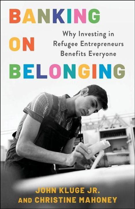 Text: „Banking on Belonging. Why Investing in Refugee Entrepreneurs Benefits Everyone. John Kluge Jr. and Christine Mahoney.“ Ein Mann arbeitet konzentriert an einem Tisch.