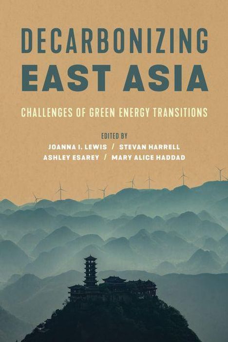 Großer Text: "DECARBONIZING EAST ASIA". Hintergrund: Illustration von Bergen mit Windturbinen und einem traditionellen Gebäude im Vordergrund.