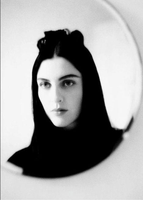 Keine Texte zu erkennen. Schwarz-weißes Porträt einer Frau mit langen, dunklen Haaren in einem runden Rahmen.